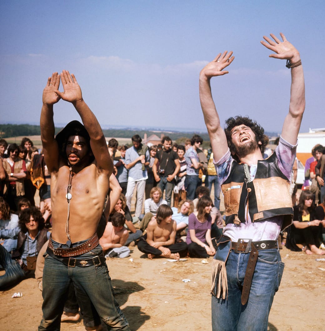 A group of hippies watch on as several others dance during the Isle of Wight Festival in 1969.