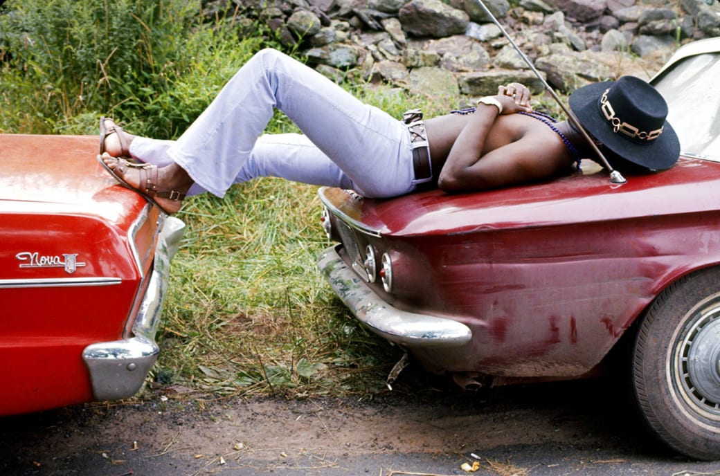 A man sleeps stretched across the trunks of two parked cars at the Woodstock Music and Arts Fair in Bethel, New York, in 1969.