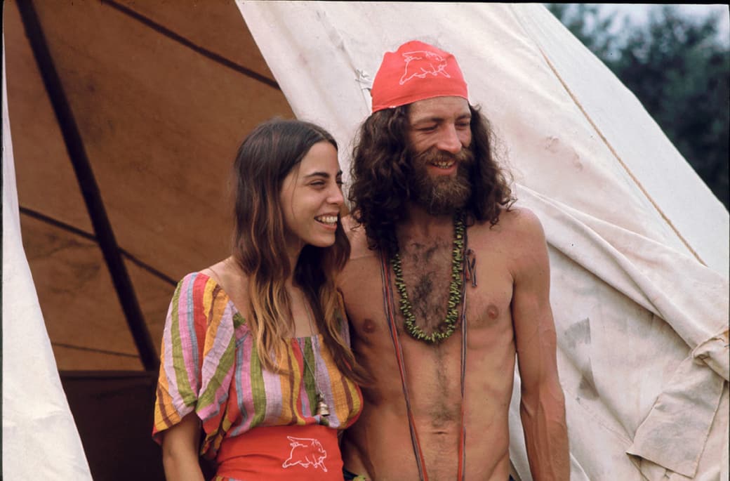 A couple attending the Woodstock Music and Arts Fair smile while standing outside the shelter they built.