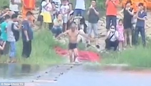 On his way: Shi Liliang, a monk from the Shaolin temple in Quanzhou city, used 200 floating plywood planks to assist his feat, which requires him to move quickly and tread incredibly lightly to succeed