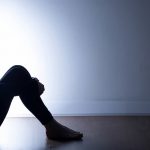 Teenager with depression sitting alone in dark room